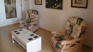 Un salon avec deux fauteuils, une table basse et plusieurs œuvres d’art encadrées accrochées au mur.