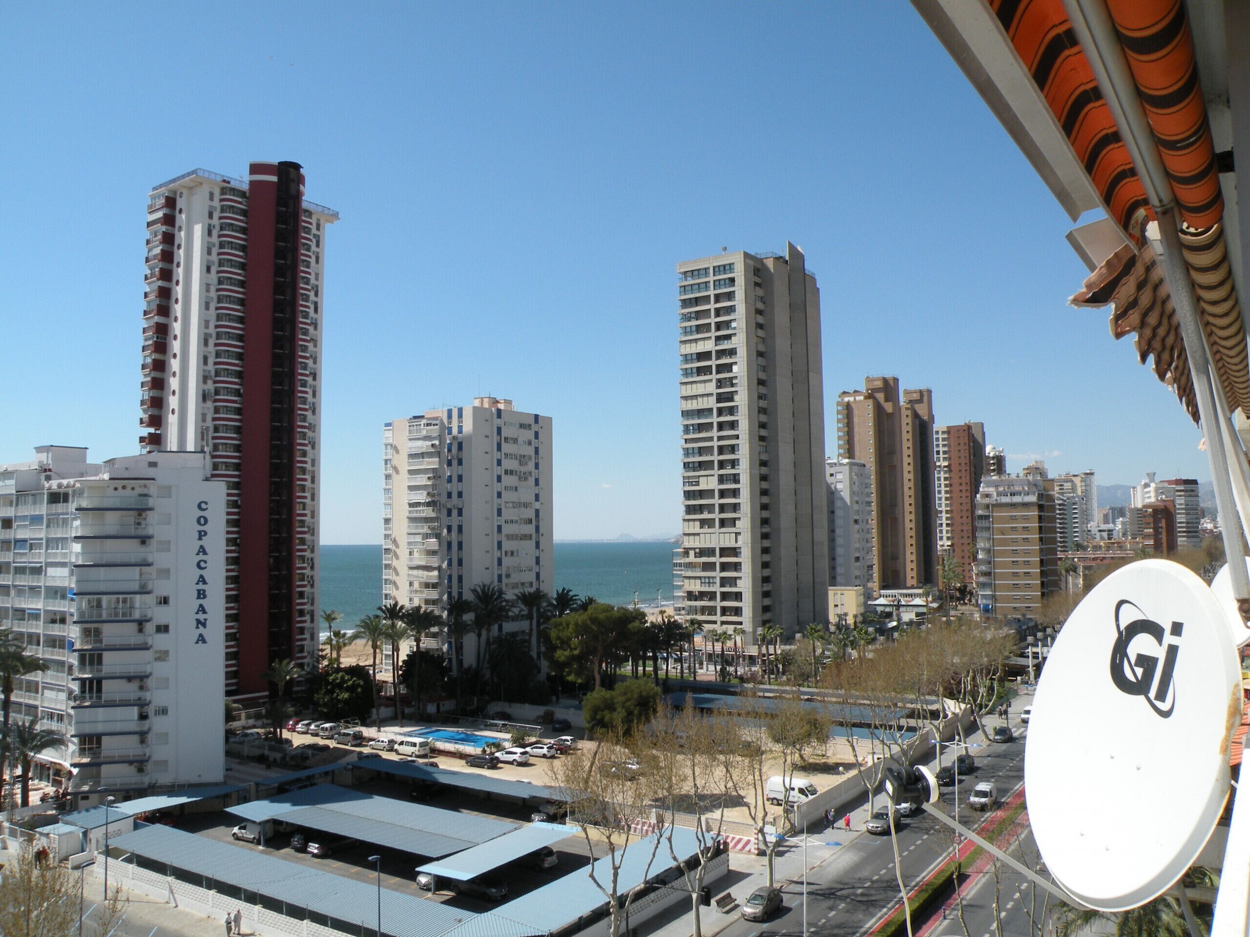 A cityscape with high-rise buildings, a clear sky, and a body of water in the background.