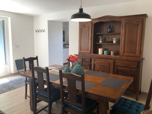 Ein Essbereich mit Holztisch, Stühlen, einer Chandelierleuchtre und einem Schrank mit Dekorationen.