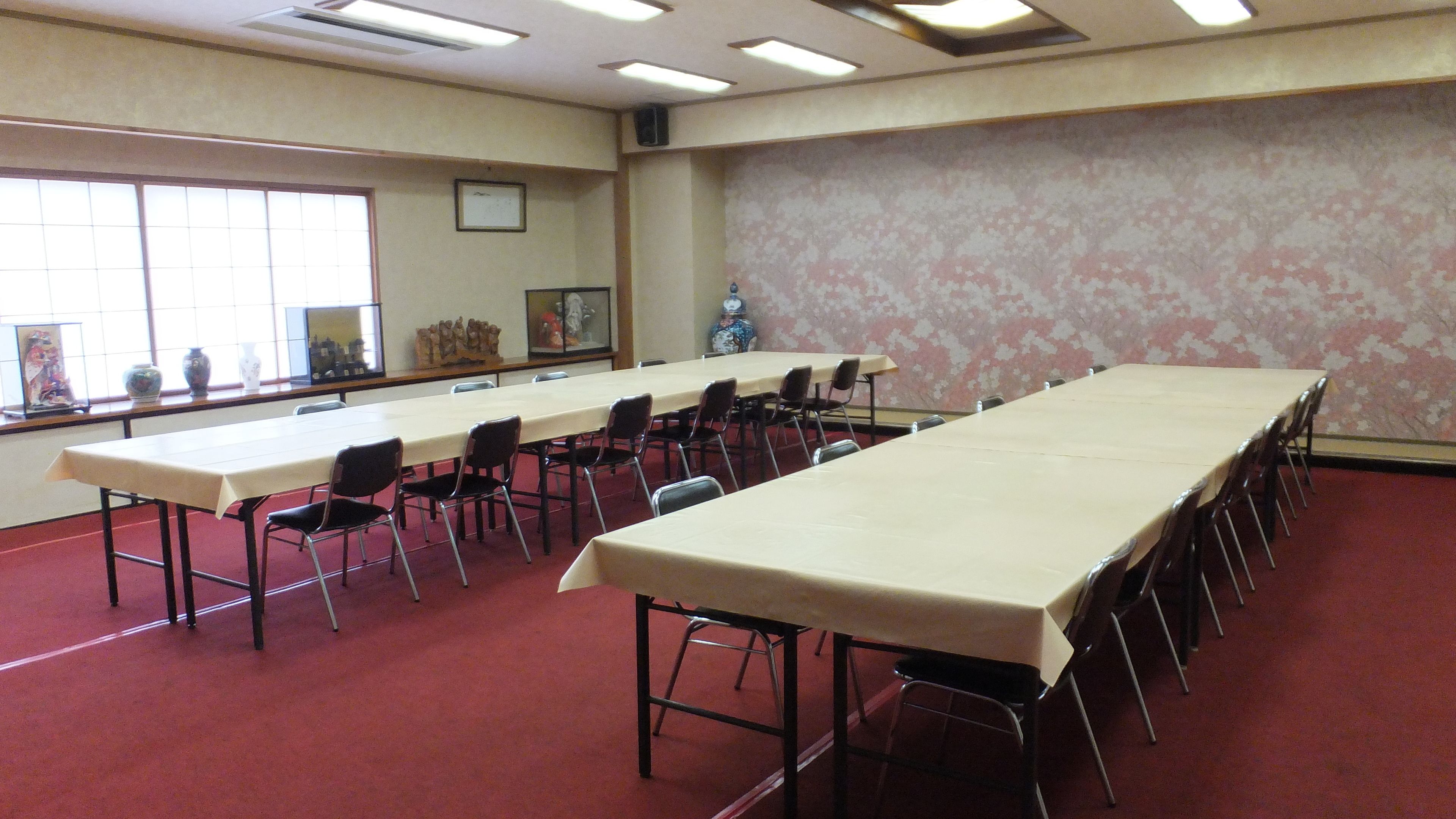A conference room with a long table and chairs, large windows, and a decorative vase.