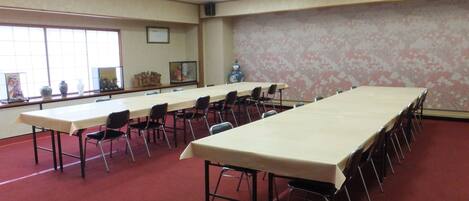 A conference room with a long table and chairs, large windows, and a decorative vase.