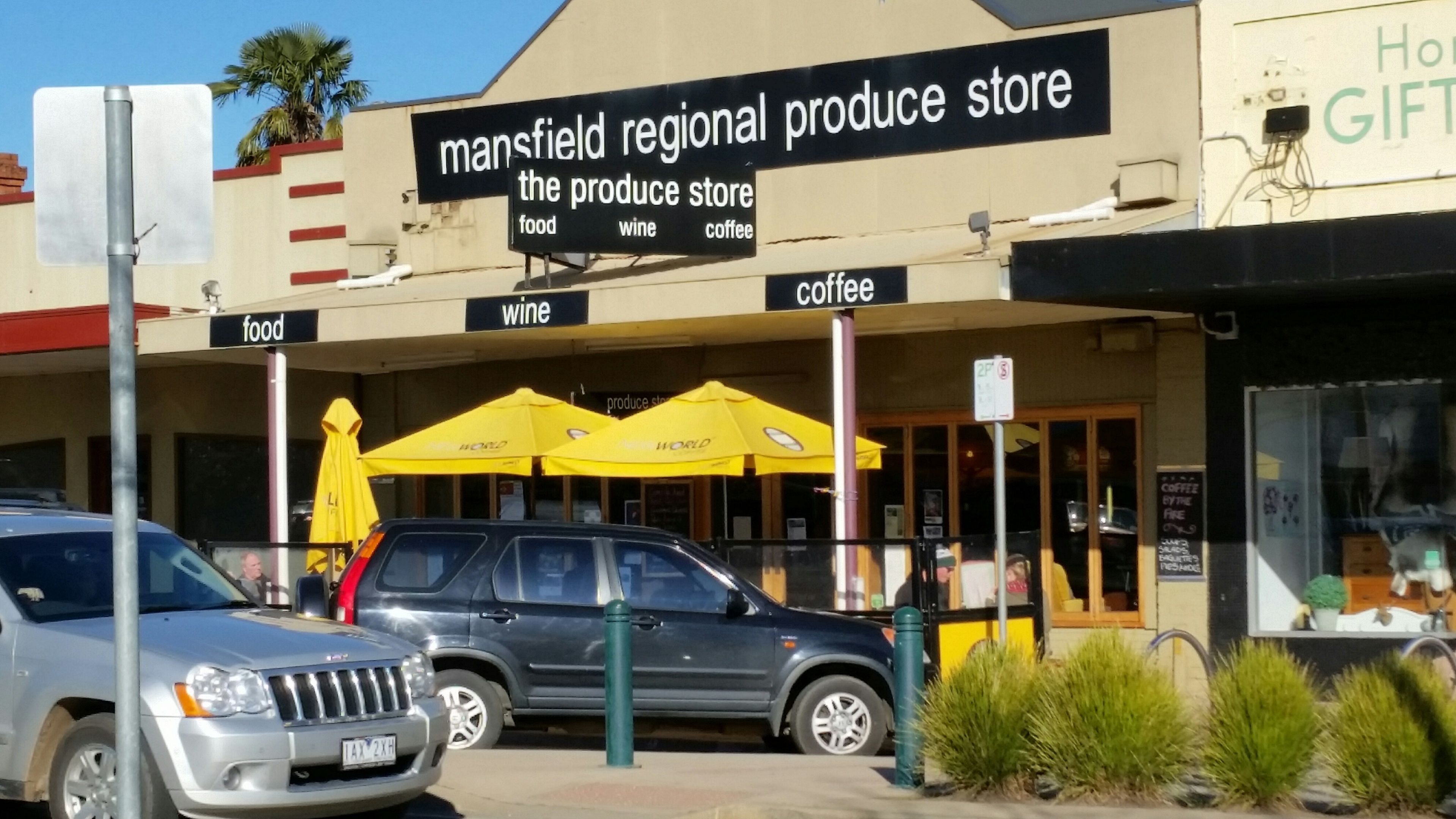 Una vetrina con insegne per 'mansfield regional produce store' e 'the produce store' che offre generi alimentari, vino e caffè.