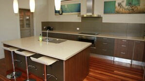 Una cocina moderna con una isla central, electrodomésticos de acero inoxidable y un ventanal con una pintura de bicicleta.