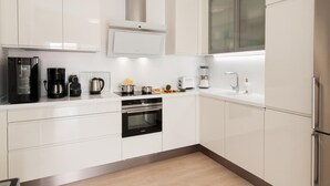 A modern kitchen with white cabinets, stainless steel appliances, and a built-in oven.