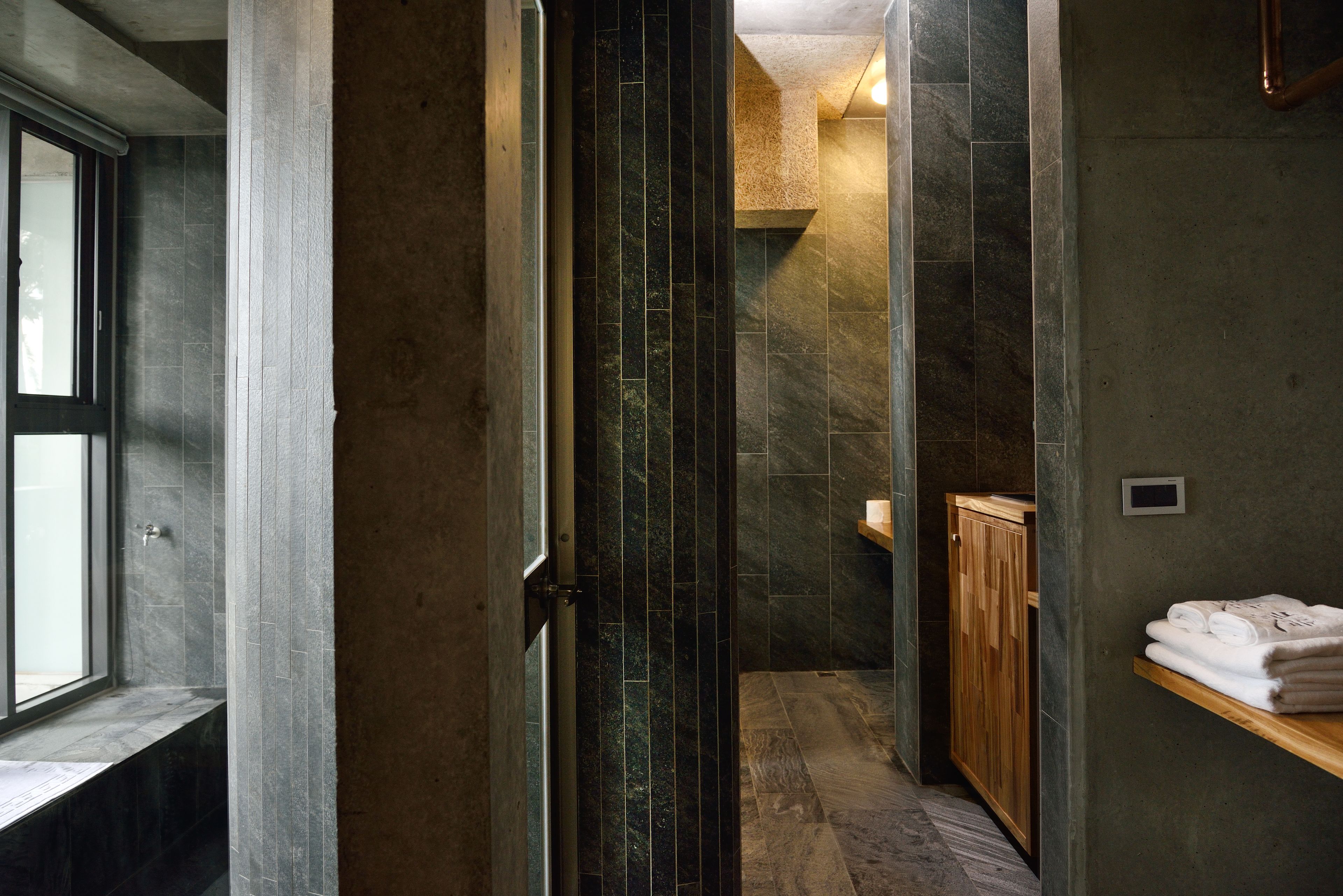 Un baño moderno con mampara de vidrio, un mueble de madera y un perchero para toallas.