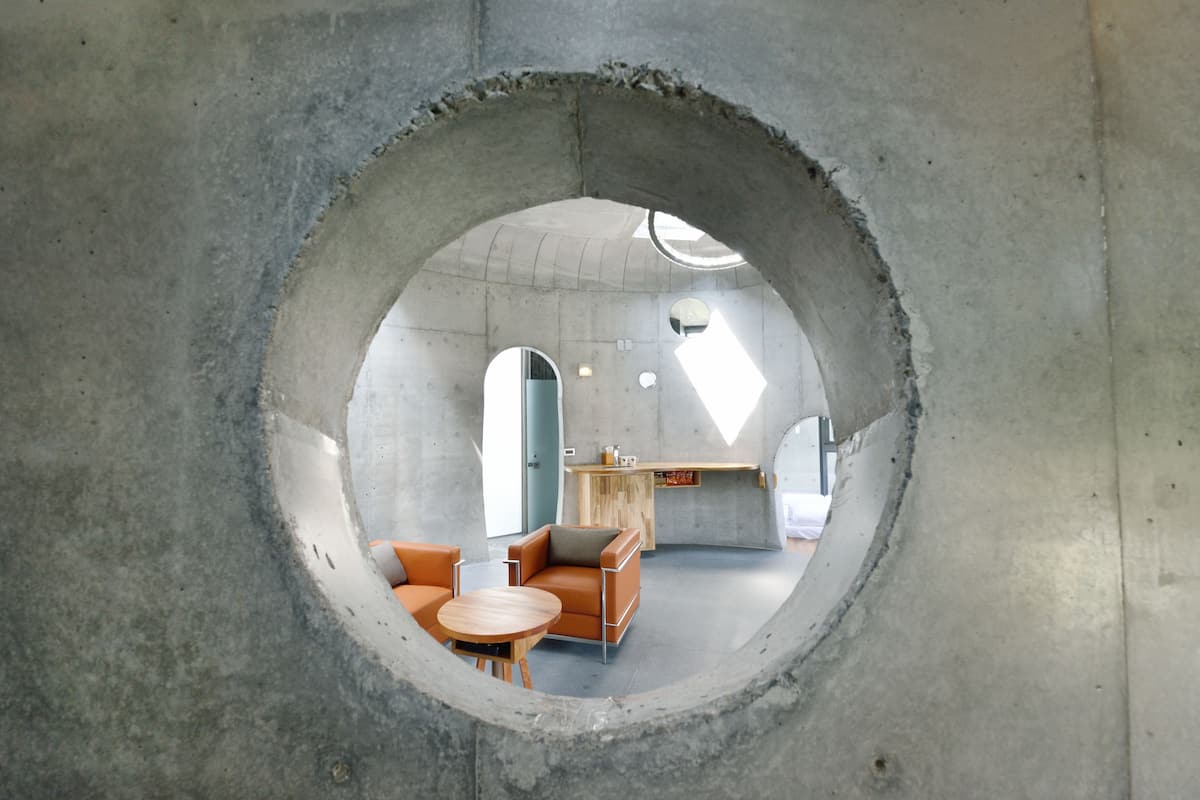 Una finestra circolare che mostra un interno moderno con un divano, un tavolo e un angolo cottura.