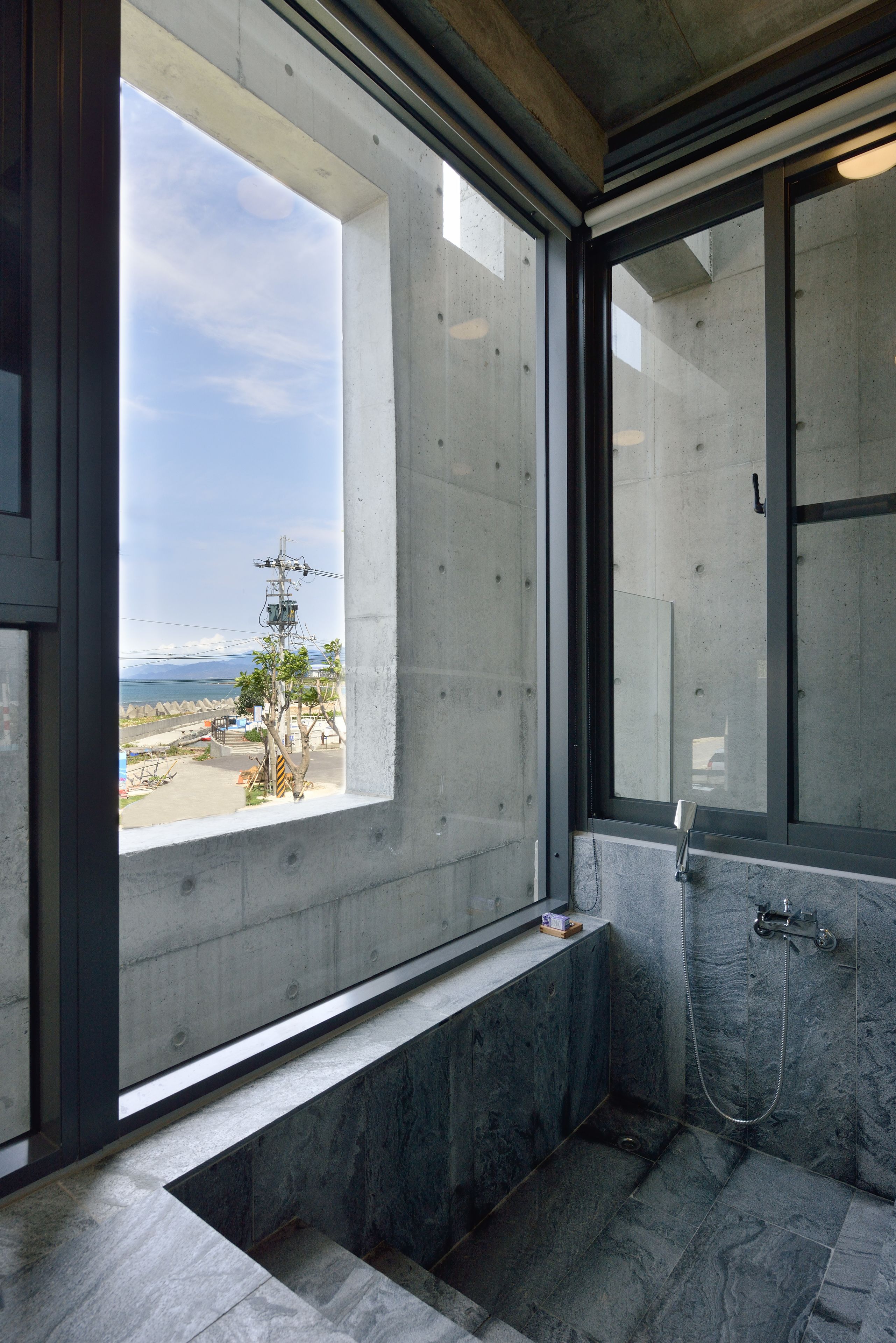 A bathroom with a large window, a bathtub, and a shower.