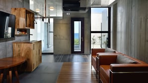 Un interior moderno con una mesa de comedor de madera, un sofá y una zona de cocina con un televisor.