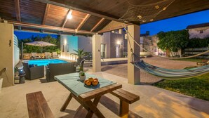 Un patio al aire libre con piscina, mobiliario y una hamaca.