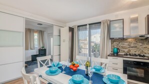 Una cocina moderna con armarios blancos, salpicadero de piedra y estufa a gas.