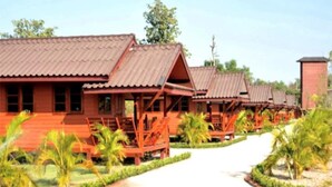 Une rangée de cabanes en bois aux toits rouges, entourées de jardins bien entretenus et de palmiers.