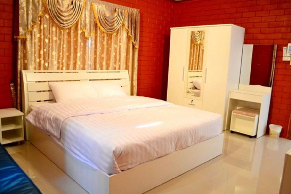 A bedroom with a white bed, a wardrobe, and a nightstand.