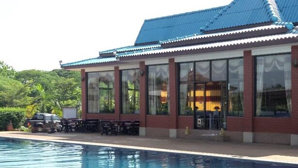 Un bâtiment doté d’un toit bleu et de grandes fenêtres, situé à côté d’une piscine.