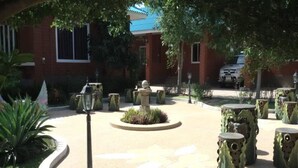Une cour intérieure avec un parterre circulaire au centre, entourée de bancs en pierre et d’un lampadaire.