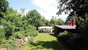 A grassy pathway leading to a house with a red roof, surrounded by lush greenery and a stone wall. - Vacation apartment Stör - Ferienhof Röhling between Schlei and Baltic Sea (Kappeln)