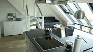Una cocina moderna con una isla de vidrio, estufa integrada y un comedor con mesa y sillas.