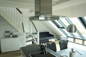 A modern kitchen with a dining area, a staircase, and a large window providing a view of the outdoors.