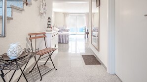 Un couloir avec un escalier, un coin repas avec une table et des chaises, et une vue sur un balcon doté d’une balustrade.