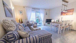 Un salon avec un canapé à rayures, une table à manger avec des chaises et un téléviseur.