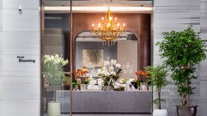 A storefront with a glass facade, a chandelier, and various potted plants. - Walkerhill Douglas House (Seoul)