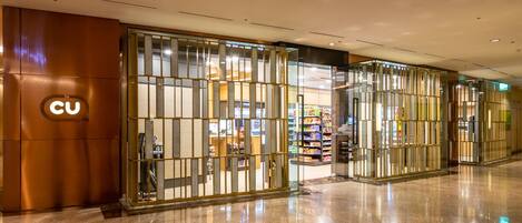 A modern hotel entrance with a CU logo, glass partitions, and a well-lit interior.