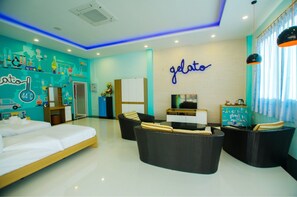 Een moderne hotelkamer met een bed, twee zwarte rieten banken, een televisie en een muur met een 'gelato'-bord.
