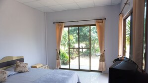 A hotel room with a large bed, a TV, and a sliding glass door leading to a garden. - Kedsila Hometel (Pathio)