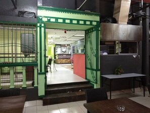 A restaurant with a green entrance, a reception desk, and a seating area with tables and chairs. - Petaling Street Hotel Chinatown (Kuala Lumpur)