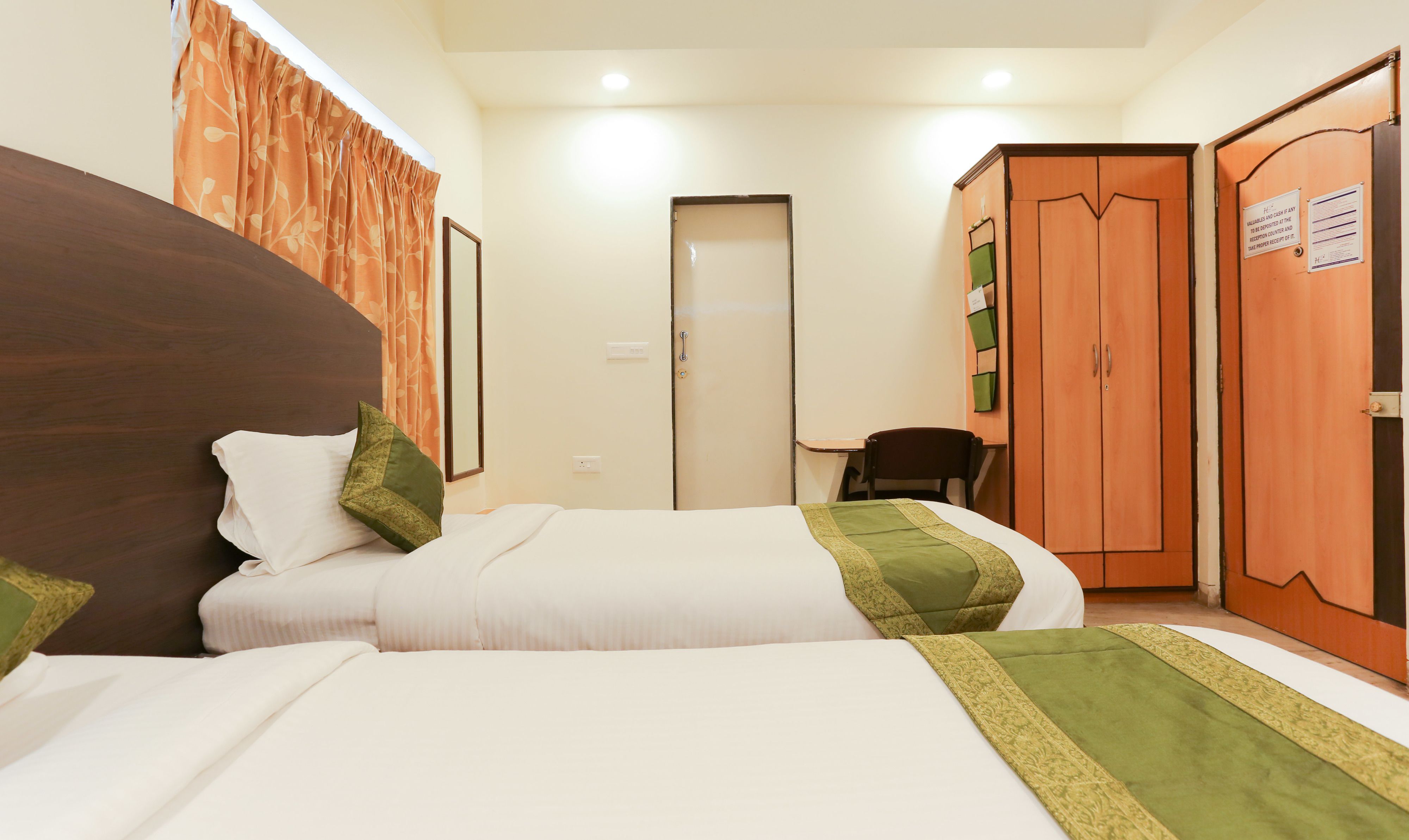A hotel room with two beds, a desk, and a wardrobe.