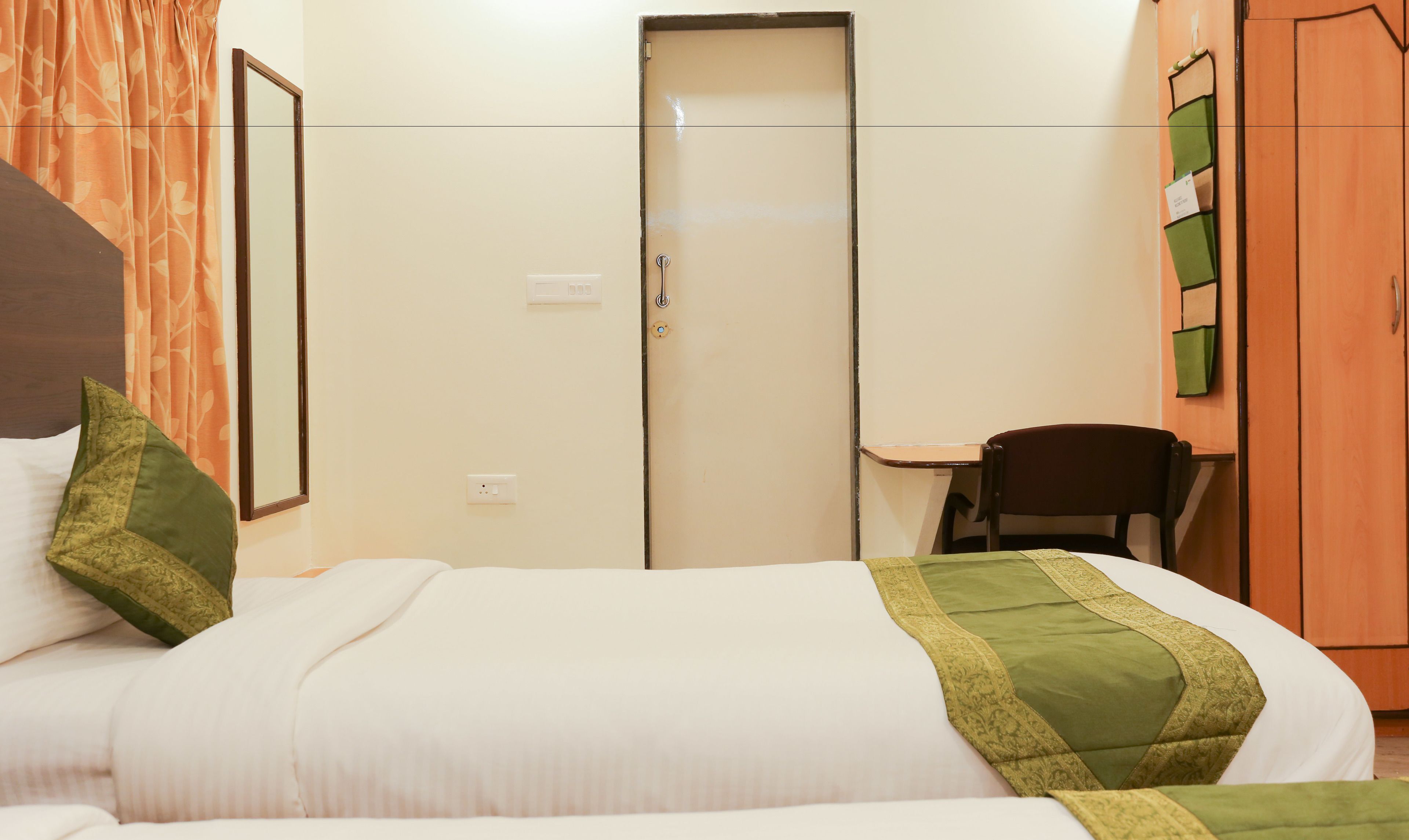 A hotel room with a bed, a desk, a chair, and a wardrobe.