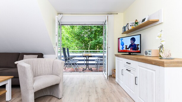 En moderne stue med sofa, fjernsyn og spiseområde.