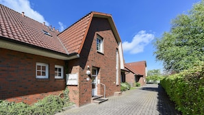 En rødstensbygning med tegltag, en lille indgang og en belagt indkørsel.