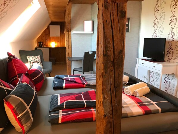 A cozy room with a sofa, a wooden beam, a television, and a desk.