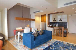 Una sala de estar moderna con un sofá azul, una mesa de comedor y una zona de cocina al fondo.
