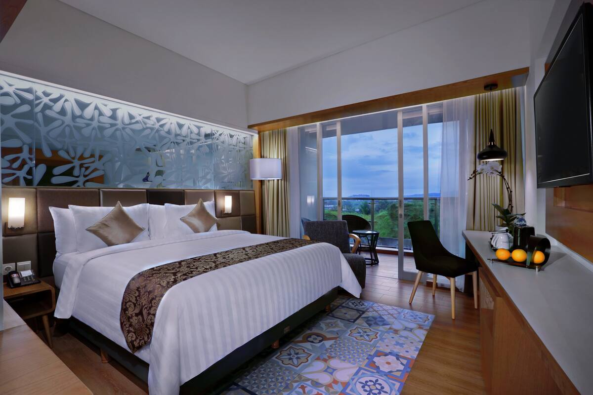 Ein modernes Hotelzimmer mit einem großen Bett, einem Schreibtisch und Blick ins Freie.