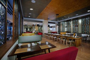 A modern restaurant with wooden tables and chairs, a bar area, and decorative wall panels.