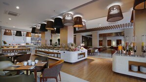 Un hall d’hôtel moderne doté d’un bar central, de différents espaces aménagés pour s’asseoir et d’un comptoir de réception.