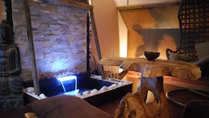 Una habitación con pared de piedra, una mesa de madera con velas y una estatua de Buda.