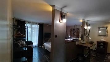 A hotel room with a bed, a desk with a chair, a mirror, and a bathroom with a sink and toilet.
