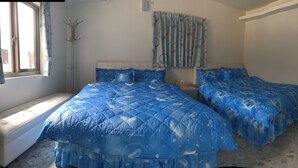Een slaapkamer met twee bedden, een raam met gordijnen, een kapstok en een wandairconditioner.
