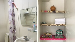 Een badkamer met toilet, wastafel, douchegordijn, spiegel en planken met toiletartikelen.