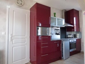 A compact kitchen with red cabinets, a microwave, a toaster, and a small refrigerator. - 3-star apartment in Arcachon house (Arcachon)