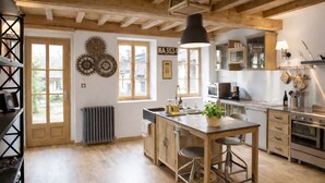Una cocina con vigas de madera, una isla central y un ventanal.