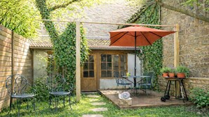 Un patio con una mesa, sillas, un perro y plantas en macetas.