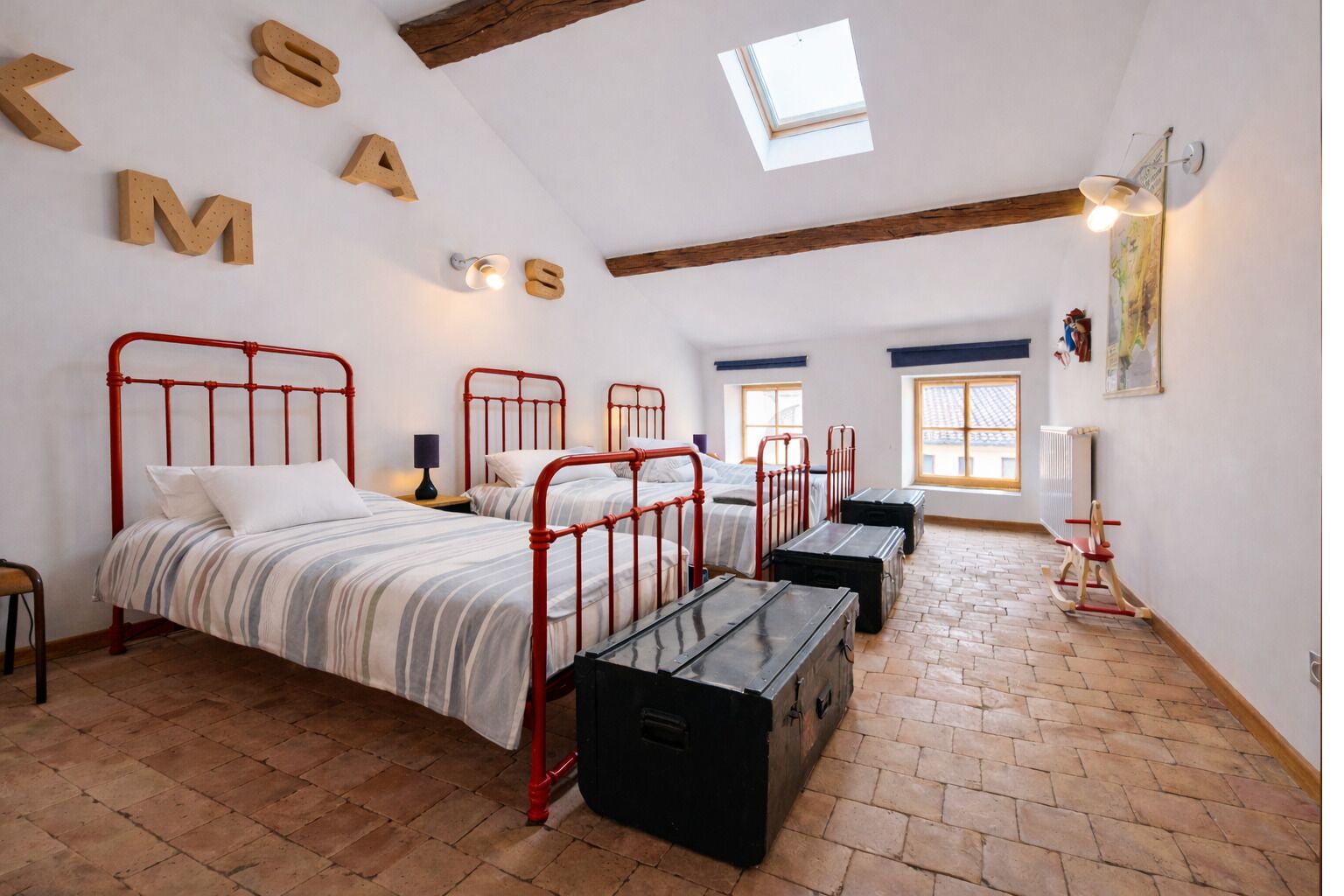 A room with two beds, a skylight, a radiator, and a wooden floor.
