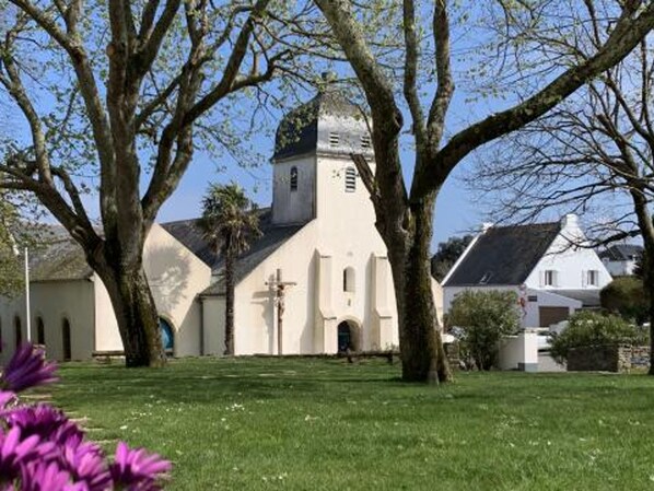 Eine Kirche mit einem Glockenturm, umgeben von Bäumen und einer grünen Wiese.