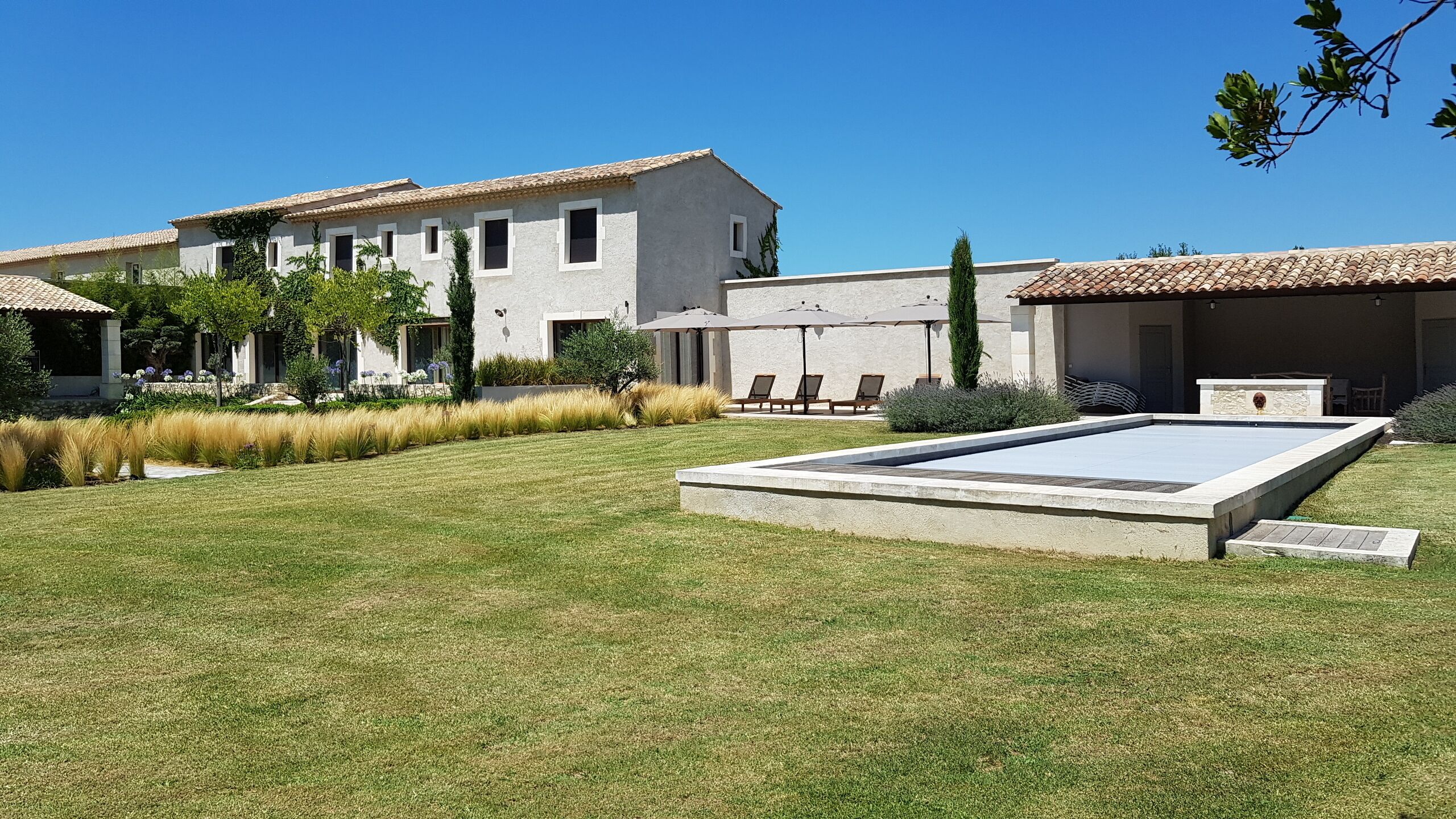 A modern villa with a swimming pool, a covered patio, and a well-maintained garden.