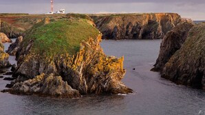 Un paysage côtier caractérisé par des falaises rocheuses et un phare.