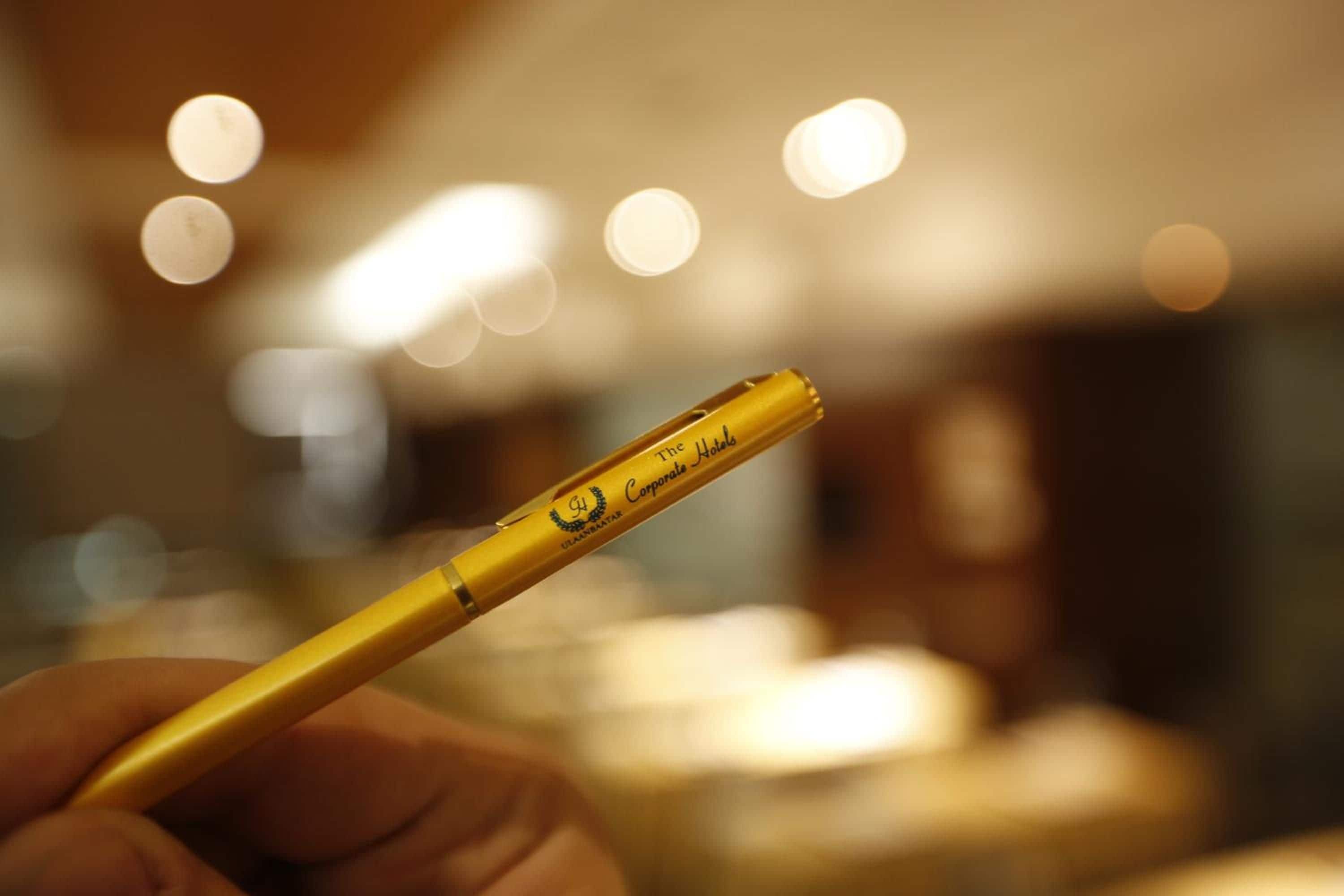 Una mano sostiene un objeto amarillo con texto, sobre un fondo desenfocado con efectos de bokeh luminosos.