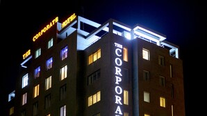 Um edifício alto com letreiros iluminados que dizem "The Corporate Hotel".